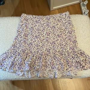Ljusgul blommig kjol från Lindex - Supersöt ljusgul kjol från Lindex med lila och ljust lila blommönster. Kjolen har volang nertill och resår i midjan för extra komfort. Perfekt för dig som gillar romantiska och somriga vibes! Varann finns inte längre då varann är köpt för två årsedan. Kjolen är i mycket bra skick. Om ni har frågor är det bara och skriva💕