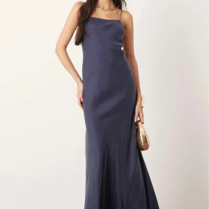 Mörkblå långklänning med tunna axelband - Elegant mörkblå långklänning med smala axelband och öppen rygg. Klänningen har en slimmad passform upptill och faller snyggt längs kroppen. Perfekt för festliga tillfällen och bal. Helt oanvänd och fortfarande i orginal förpackning🌟 köpt för 1700kr säljer för 800kr!!