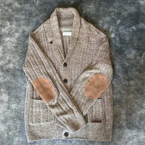  stickad kofta från Pier One - Säljer en beige stickad kofta från Pier One. Koftan har bruna mockadetaljer på armbågarna och två fickor framtill. Koftan är i mycket är i nyskick!