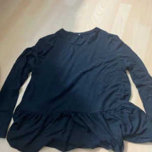 Svart volangtröja från ONLY - Säljer en svart långärmad tröja från ONLY med volangdetalj nedtill. Tröjan har rund halsringning och är i ett mjukt material som passar perfekt till vardags. Enkel och stilren design.