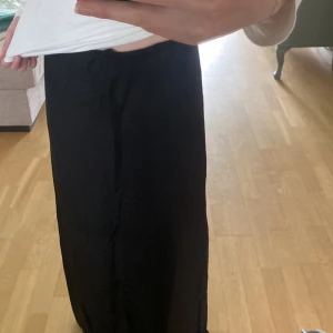 Svarta vida byxor från H&M - Säljer en helt ny svart långkjol från H&M i storlek S. Den har en låg midja och är tillverkad i ett lätt och luftigt material, perfekt för en avslappnad och trendig stil. Aldrig använd (prislapp kvar)💕