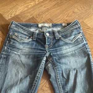 Blå lågmidjade bootcut jeans - Skit snygga extremt lågmidjade jeans. De har blivigt inlämnade till en skreddare som förklarar stygnen som finns på dem.