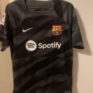 FC Barcelona svart bortatröja Nike - Säljer en svart FC Barcelona bortatröja från Nike med Spotify-logga på bröstet och klubbmärke. Tröjan har korta ärmar och subtilt mönster i olika nyanser av svart. Perfekt för dig som vill visa ditt stöd för Barca. Tröjan är aldrig använd. Skriv för funderingar eller frågor💯💯💯