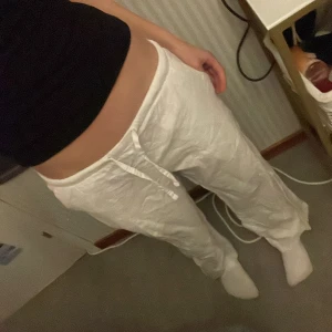 Vita linnebyxor från Gina Tricot - Säljer tyvärr mina vita linnebyxor från Gina Tricot med dragsko i midjan. Byxorna har en avslappnad passform och raka ben, perfekta för varma dagar. Lätta och luftiga med resår i midjan för extra komfort.  55% linne och 45% bomull. Bra sikck inga märken eller fläckar. Sparsamt andvända.