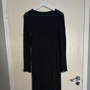 Svart långklänning  - Långklänning från Gina Tricot Elegant långklänning med lätt transparent tyg och fastsydd underklänning som ger ett stilrent och bekvämt intryck. Perfekt till både festligare tillfällen och vardag med rätt accessoarer.                                                   Använd en gång