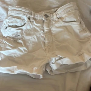 Vita jeansshorts från LAB Industries - Säljer ett par vita jeansshorts från LAB Industries. De har klassisk femficksdesign, knapp och dragkedja framtill samt lätt slitning vid ena fickan. Shortsen är högmidjade och har en normal passform. Säljer pågrund av dålig användning.💖