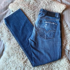 Blå Diesel Larkee jeans med slitningar - Säljer ett par sjukt snygga blå Diesel jeans med slitna detaljer och ljusa partier framtill. Sjukt unik och stilren tvätt. Modellen heter Larkee och är rak passform med klassisk femficksmodell. Märkespatch bak i midjan och tydliga slitningar från fabrik vid fickor och lår. Jeansen är i väldigt bra skick, 9/10. Tveka inte på att höra av dig vid frågor eller funderingar!