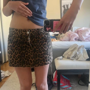 Leopardmönstrad minikjol - Säljer en snygg leopardmönstrad minikjol med klassisk femficksdesign och rå kant nertill. Kjolen har normal passform och är perfekt för dig som vill sticka ut med ett djurmönster. Dragkedja och knapp framtill.