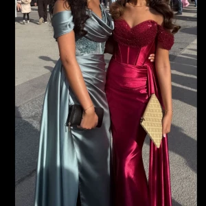 Turkos  axelbandslös balklänning med paljetter - Säljer en turkoslångklänning med axelbandslös design och glittrig paljettöverdel. Klänningen har markerad midja, figurnära passform och en elegant slits. Perfekt för bal eller fest! Storlek 38/36 Endast använd några timmar 