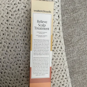 Waterclouds Relieve Scalp Treatment - Waterclouds Relieve Scalp Treatment är en parfymfri leave-in behandling för torr och känslig hårbotten. Innehåller Seascalp biomarine och Xpertmoist som återfuktar och lugnar utan att tynga ner håret. Kommer i en beige och vit förpackning med text i svart.