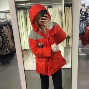 Röd pufferjacka från Svea - Säljer en riktigt fet röd pufferjacka från Svea med silvriga detaljer upptill. Jackan har stor huva, dragkedja och stora fickor framtill. Perfekt för kalla dagar när du vill sticka ut och hålla dig varm. Oversized fit för skön vibe.