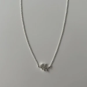 Silverhalsband med bladberlock - Ett stilrent halsband i silver med en tunn kedja och en liten bladformad berlock i mitten. Köpt på glitter för ganska mycket då det är gjort i riktig är silver och går utmärkt att ha på sig utan att färgen förändras. Varsamt användt<3