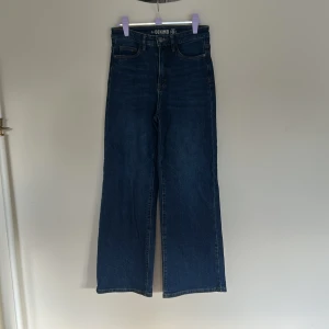 Mörkblå wide jeans med hög midja - Snygga mörkblå jeans från Denim med hög midja och raka, vida ben. Klassisk femficksmodell i kraftigt jeanstyg som ger en cool och avslappnad look. Perfekta att matcha med sneakers eller boots.