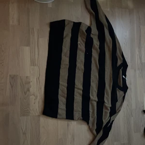 Randig stickad tröja från Xlnt 2XL - Säljer en oversized stickad tröja från Xlnt i storlek 2XL. Tröjan har breda svarta och bruna ränder, lång ärm och en loose fit. Perfekt för dig som gillar chill och avslappnad stil.
