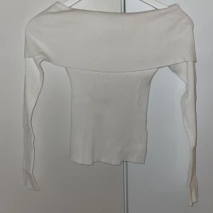 Vit offshoulder topp från BikBok - Supersnygg vit ribbad offshoulder topp från BikBok i storlek S. Toppen har långa ärmar och en bred kant över axlarna som ger en trendig look. 