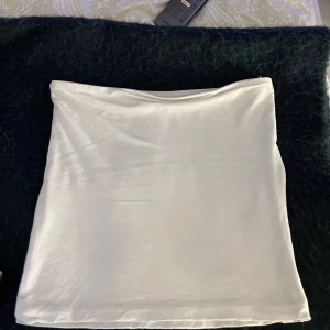 Vit tubtopp  - Säljer en stilren vit tubtopp från C i storlek S. Toppen är axelbandslös och har en enkel, clean design som är lätt att matcha med olika outfits. Materialet känns mjukt och stretchigt, perfekt för varma dagar eller lager-på-lager.