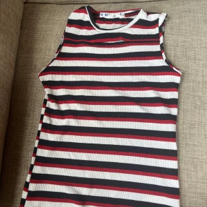 Randig ribbad linnetopp från Candy Couture - ribbad ärmlös topp från Candy Couture. Toppen har en cool cut-out detalj vid halsen och sitter super fint, perfekt till fest eller middag. Storlek xs/s