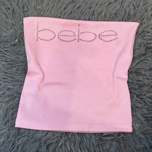 Rosa ribbad tubtopp från Bebe - Bebe supersöt ljusrosa ribbad tubtopp med glittrande stenar som bildar loggan framtill. Toppens material är stretchigt. Köpt på vinted och passade ej (lånade bilder) Pris kan diskuteras 💕