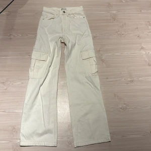 Krämvita cargojeans från ginatricot - Stilrena krämvita cargojeans från gina med raka ben och stora sidofickor. Fint skick, använda fåtal gånger. 