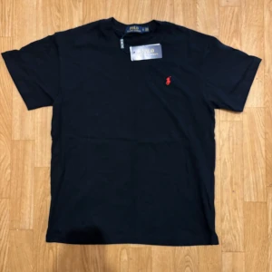 Svart t-shirt Polo Ralph Lauren - Svart t-shirt från Polo Ralph Lauren med klassisk röd broderad logga på bröstet. T-shirten har rund halsringning och korta ärmar. Tillverkad i mjuk bomull.