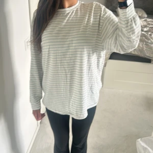 Vit och ljusgrå randig långärmad tröja - Säljer en oversized långärmad tröja med vita och ljusgrå ränder. Tröjan har en avslappnad passform och är tillverkad i mjuk bomull, perfekt för chill dagar. Klassisk rund halsringning och raka ärmar. Superenkel att styla till jeans eller leggings.