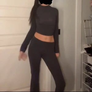 Mörkgrå croppad långärmad tröja - Säljer en mörkgrå croppad långärmad tröja med tight passform. Tröjan har en hög hals och är tillverkad i ett stretchigt material som sitter snyggt på kroppen. Perfekt för dig som gillar en stilren och enkel look. säljer hela settet!!!