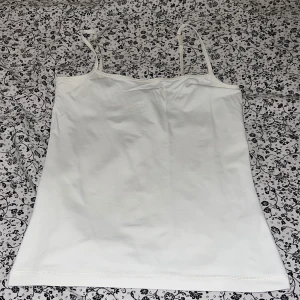 Vit linnetopp från Lindex XS - Enkel och stilren vit linnetopp från Lindex i storlek XS. Toppen har tunna axelband och rak passform, perfekt att matcha med jeans eller kjol. Tillverkad i mjuk bomull som känns skön mot huden. Snygg basic som funkar till många olika looks.