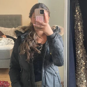 Svart Parajumpers pufferjacka XS - Säljer en svart pufferjacka från Parajumpers med snygg fuskpäls på huvan och gul detalj vid dragkedjan. Jackan har quiltad design, lång ärm och är perfekt för kalla dagar. Slim fit och riktigt skön att bära. Priset kan alltid diskuteras 