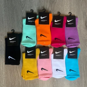 Färgglada Nike strumpor i 20-pack - Säljer ett 20-pack ribbade Nike strumpor i olika färger: svart, mintgrön, orange, ceriserosa, lila, gul, ljusrosa, vit och turkosblå. Klassisk Nike-logga på sidan. Perfekta för att addera färg till din outfit och riktigt sköna på foten. 