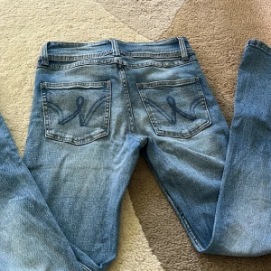 Blå jeans  - Säljer ett par klassiska blå jeans från Gina Tricot i storlek 158. Jeansen har raka ben, dubbla knappar i midjan och snygga broderade bakfickor. 