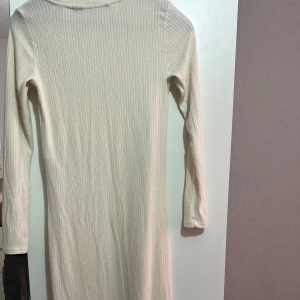 Ribbad vit långärmad klänning Vero Moda - Säljer en ribbad, vit långärmad klänning från Vero Moda i storlek XS. Klänningen har en enkel och stilren design med rund hals och smal passform. Perfekt för dig som gillar minimalistisk stil och vill ha något bekvämt men snyggt. Priset kan diskuteras vid snabb affär 😊