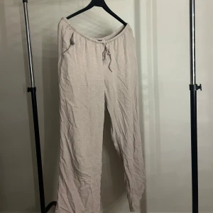 Beiga linnebyxor från Divided - Luftiga och sköna beiga linnebyxor från Divided med dragsko i midjan. Perfekta för chill dagar eller när du vill ha en avslappnad stil. Byxorna har rak passform och är tillverkade i linne för en sval känsla.