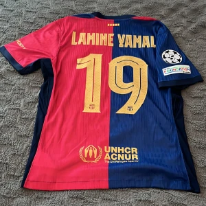 Limine Yamal) fotbollströja  - 😮‍💨 Säljer en riktigt snygg FC Barcelona 23/24 Champions League-tröja med Lamine Yamal #19 på ryggen – en framtida superstjärna!  ✅ Officiella tryck och märken ✅ Champions League-patch + UEFA Foundation-badge ✅ UNHCR-logga på ryggen ✅ Ikoniska Spotify-loggan på bröstet ✅ Aldrig använd utomhus – i nyskick! 👌  Skick: Som ny 📏 Storlek: (Fyll i din storlek här) 📦 Kan skickas eller hämtas i (din stad)  Skynda dig – det här är inget man ser varje dag 😮‍💨 Skicka ett meddelande vid intresse! 👌