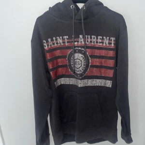 Grå Saint Laurent hoodie med tryck - Tja! Säljer denhär eftertraktade hoodien från Saint Laurent. Storlek S men passar Xs.