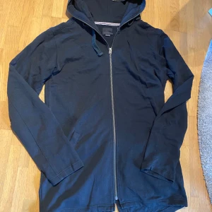 Huvtröja  - Längre huvtröja med fickor. Lite längre bak med liten slits