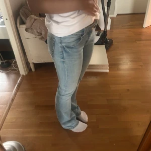 Ljusblå bootcut jeans - Säljer ett par ljusblå jeans med bootcut-modell och låg midja. Jeansen har klassisk femficksdesign och är tillverkade i mjukt denimtyg. Perfekta för dig som gillar en avslappnad men ändå snygg stil.