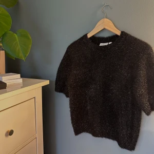 Svart fluffig tröja från Kappahl - Svart glittrig tröja med puffärmar - i toppskick. Använd ett fåtal gånger.   Passar lika bra till vardags med ett par jeans som till fest med kostymbyxor eller kjol! 