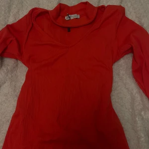 Röd ribbad polotröja från Paul Mark - Säljer en snygg röd polotröja från Paul Mark i storlek S. Tröjan har ribbad struktur, lång ärm och v-ringad hals med en hög krage. Perfekt för dig som gillar färgstarka och stilrena plagg med lite edge.
