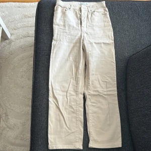 Beiga raka jeans från NA-KD - Snygga beiga jeans från NA-KD med raka ben och klassisk femficksdesign. Byxorna har hög midja och är tillverkade i ett mjukt bomullsmaterial. 