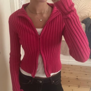 Rosa ziptröja - Säljer en rosa ribbad kofta. Koftan är väldigt lång i ärmarna och den går att styla på massor med olika sätt. Den sitter åt rätt tight och ger verkligen din outfit en pop of colour! På sista bilden ser man att den börjat bli lite nopprig på undersidan av armarna. Men annars är den i perfekt skick!💗