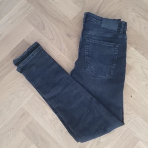 Svarta jeans från Jack & Jones - Snygga svarta slim jeans från Jack & Jones i stretchigt jeanstyg. Klassisk femficksmodell med smal passform och normal midja. Perfekta för dig som gillar en tajt look och vill ha bekväma jeans med stilren vibe. De är i modellen slim glenn och storlek 164. Det är bara att höra av er vid minsta fråga eller fundering! 