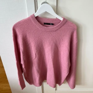 Rosa stickad tröja från 157 - Mysig rosa stickad tröja från 157 med rund halsringning och ribbade muddar. Perfekt för lager-på-lager och chill dagar. Långärmad och i en skön loose passform som ger en avslappnad vibe.