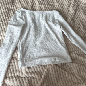Vit spetsblus från Kappahl - Supersöt vit långärmad blus från Kappahl med broderade spetsdetaljer och diskret hålmönster. Blusen har en rak passform och är perfekt för dig som gillar en romantisk och fräsch stil. Materialet känns mjukt och luftigt mot huden. En liten fläck på baksidan se på sida 4