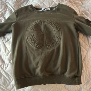 Olivgrön Stone Island sweatshirt S - Säljer en olivgrön sweatshirt från Stone Island i slim fit med stort broderat logomärke på bröstet och klassisk patch på ärmen. Tröjan har rund hals, ribbade muddar och är tillverkad i mjuk bomull. Perfekt för dig som gillar streetwear och snygga detaljer.