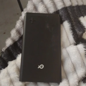 Nästan ny Powerbank  - Bilderna visar en svart powerbank från märket Poss, modell PSPBALC60BK-18 med en kapacitet på 6000mAh. Den har flera USB-portar för laddning av olika enheter. Perfekt för dig som behöver extra batteri till mobilen när du är på språng. Använd fåtal gånger 
