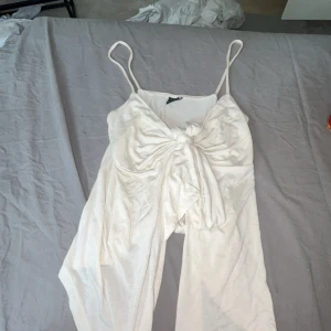 Vit linnetopp med knyt från Gina Tricot - Supersöt vit linnetopp från Gina Tricot med smala axelband och snygg knytning framtill. Perfekt för varma dagar och enkel att styla med jeans eller kjol. Tunn och lätt i materialet, ger en fräsch och somrig vibe.