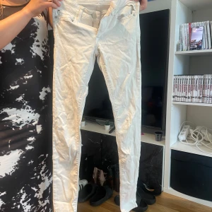 Vita skinny jeans med låg midja - Säljer ett par vita skinny jeans med låg midja och klassisk femficksdesign. Byxorna har smal passform och är perfekta för dig som gillar en clean och fräsch look. Materialet är mjukt och stretchigt för extra komfort.