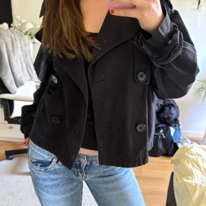 Svart trenchcoat  - Kort svart trenchcoat från ginatricot. Storlek L men liten i storleken. Köpt för 700. Skriv vid frågor👌