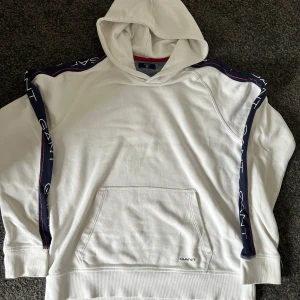 Gant hoodie  - Säljer en vit hoodie från GANT i mycket fint skick. Klassisk design, mjuk insida och perfekt passform. Stilren och tidlös – passar lika bra till vardags som till ett mer uppklätt streetwear-look.