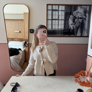 Beige stickad kofta med knyt - Superfin beige stickad kofta med två knyt framtill. Koftan har en mjuk och lite loose passform, långa ärmar och ribbad struktur. Perfekt att slänga över en topp för en chill och snygg look. Använd 1 gång, precis som ny. Passar både xs och s